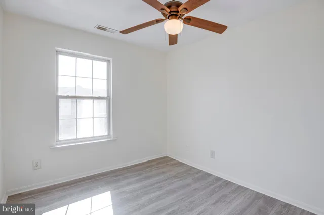 an empty room with a window and a fan