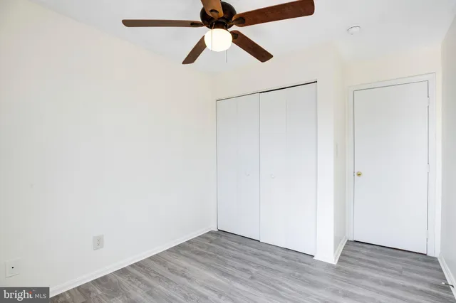 an empty room with wooden floor closet and chandelier fan