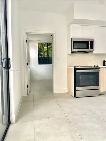 a view of kitchen with a refrigerator microwave and door