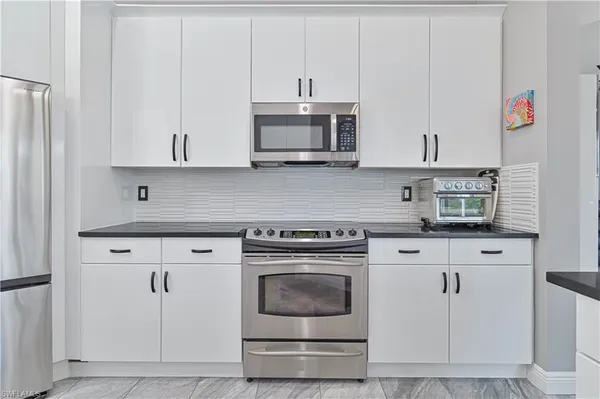a kitchen with granite countertop white cabinets and stainless steel appliances