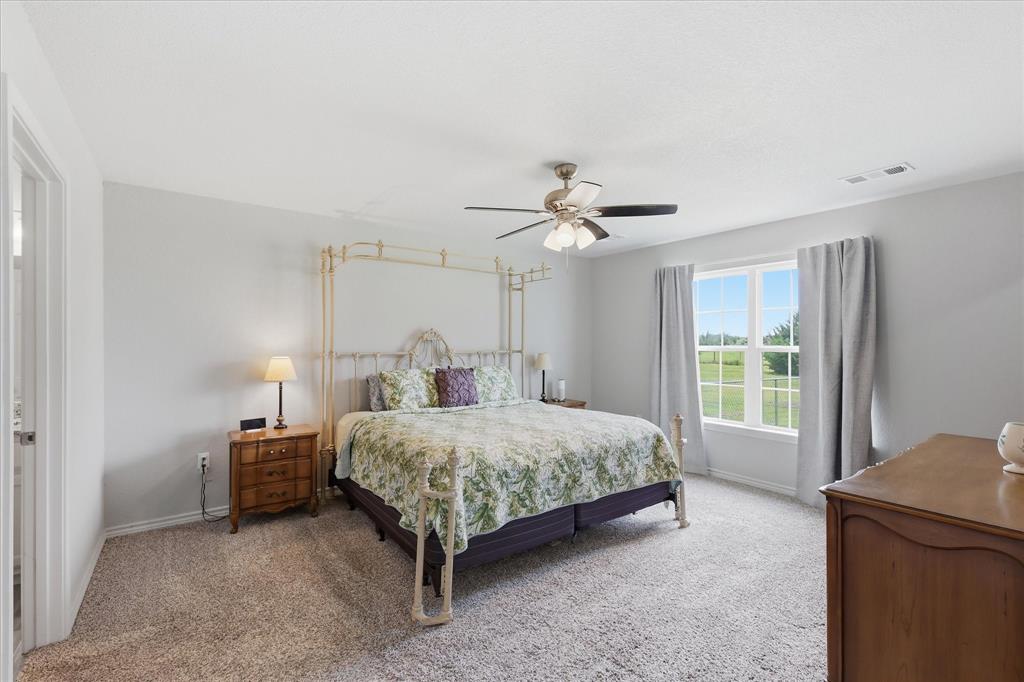 110 Highview Road Ennis, TX 75119 - Photo 17 of 40 Spacious room featuring neutral carpeting, light gray wall paint, a ceiling fan with integrated lighting, and a large window with natural light