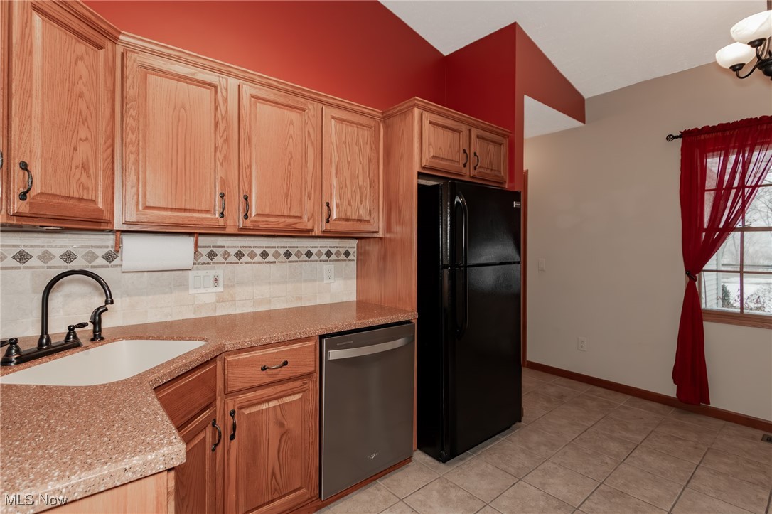 4815 South Ridge Road Perry, OH 44081 - Photo 10 of 48 Kitchen featuring freestanding refrigerator, stainless steel dishwasher, light stone counters, tasteful backsplash, and light tile patterned floors