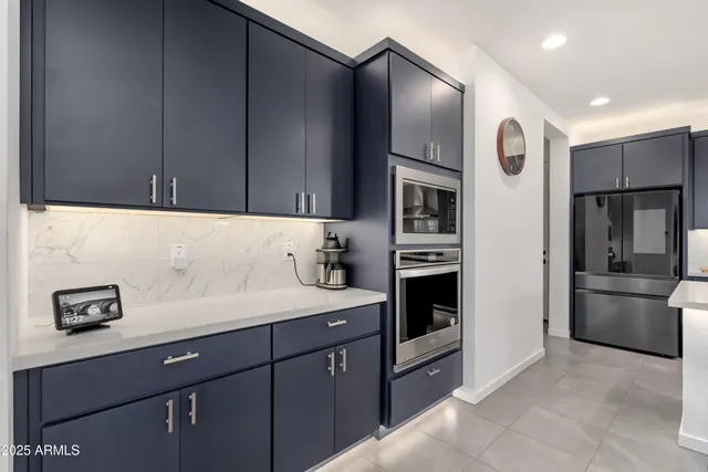 a kitchen with stainless steel appliances a refrigerator a sink and white cabinets