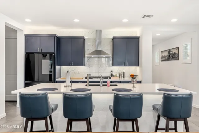 a kitchen with stainless steel appliances granite countertop a table chairs and a refrigerator