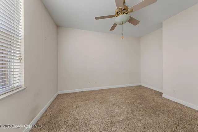 an empty room with a window and a fan