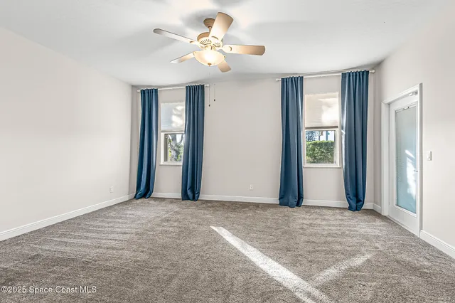 a view of a livingroom with a chandelier fan and windows