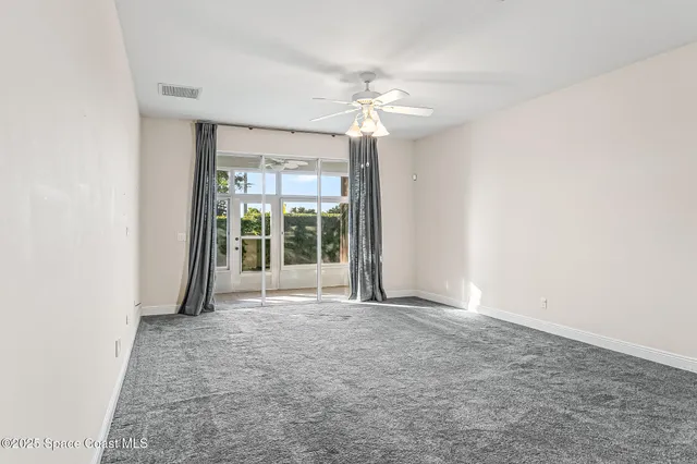 a view of a big room with windows and chandelier fan