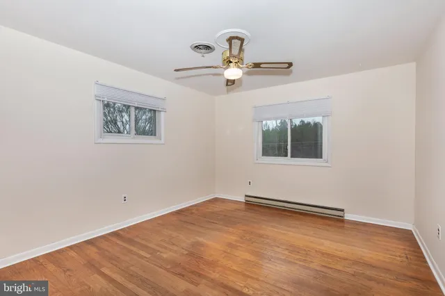 an empty room with wooden floor chandelier fan and windows