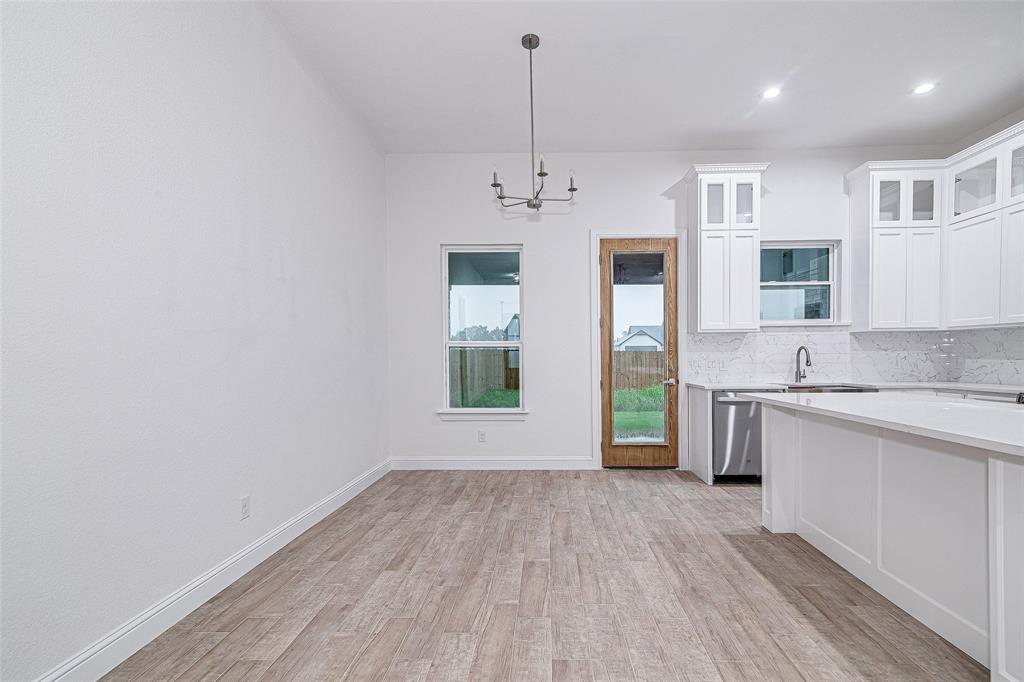 204 High Rdg Court Godley, TX 76044 - Photo 9 of 28 a view of a kitchen with a sink dishwasher a kitchen island with wooden floor and cabinets