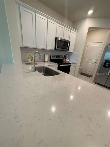 a kitchen with stainless steel appliances a sink a stove a microwave a refrigerator with grey cabinets