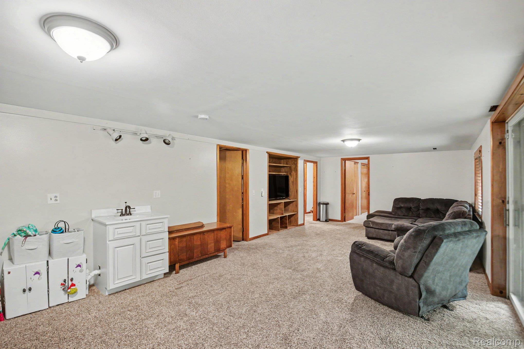 1646 Boy Scout Road Caro, MI 48723 - Photo 4 of 28 Spacious room featuring light-colored carpeting, multiple overhead light fixtures, and a white vanity with a sink
