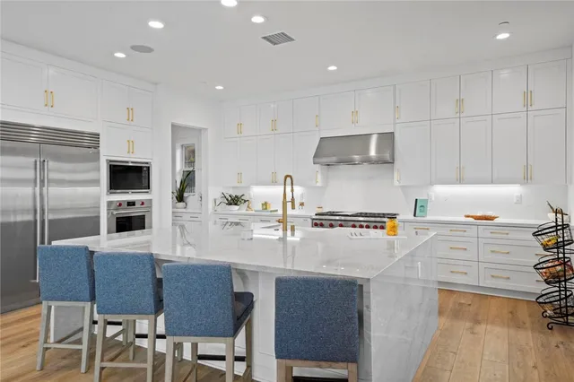 a kitchen with stainless steel appliances a stove a sink a microwave a refrigerator and cabinets