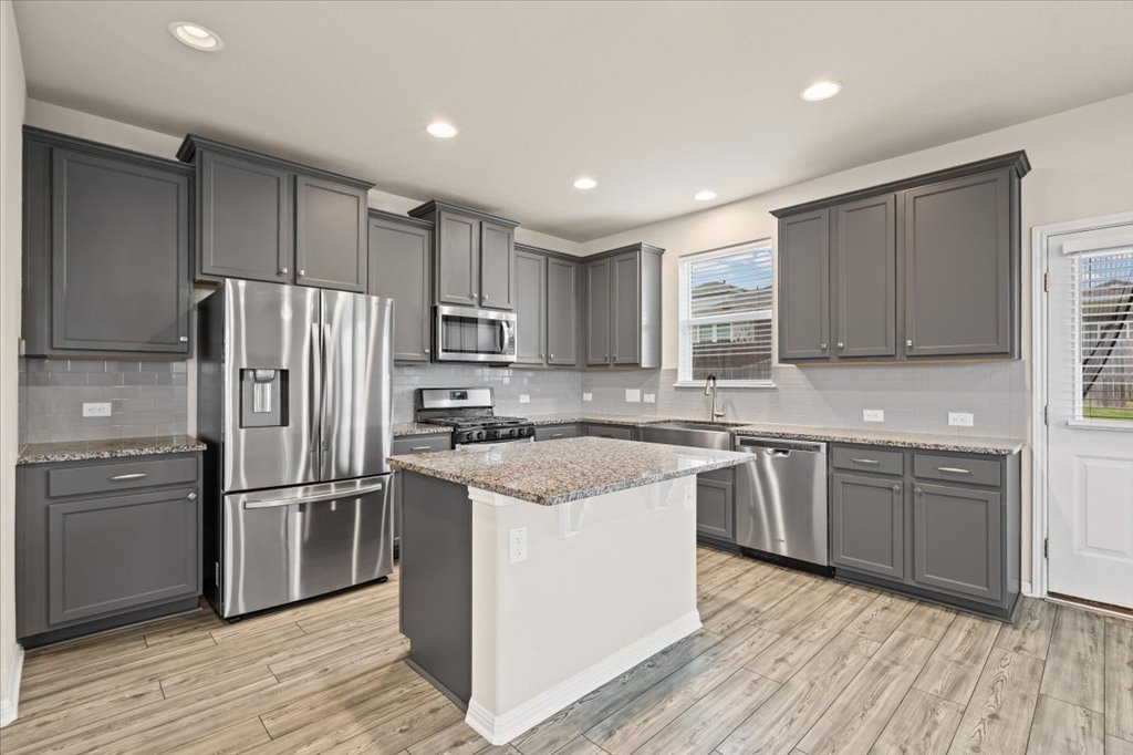 6313 Mary Lewis Drive Austin, TX 78747 - Photo 4 of 20 a kitchen with stainless steel appliances granite countertop a refrigerator a stove top oven a sink and dishwasher with wooden floor