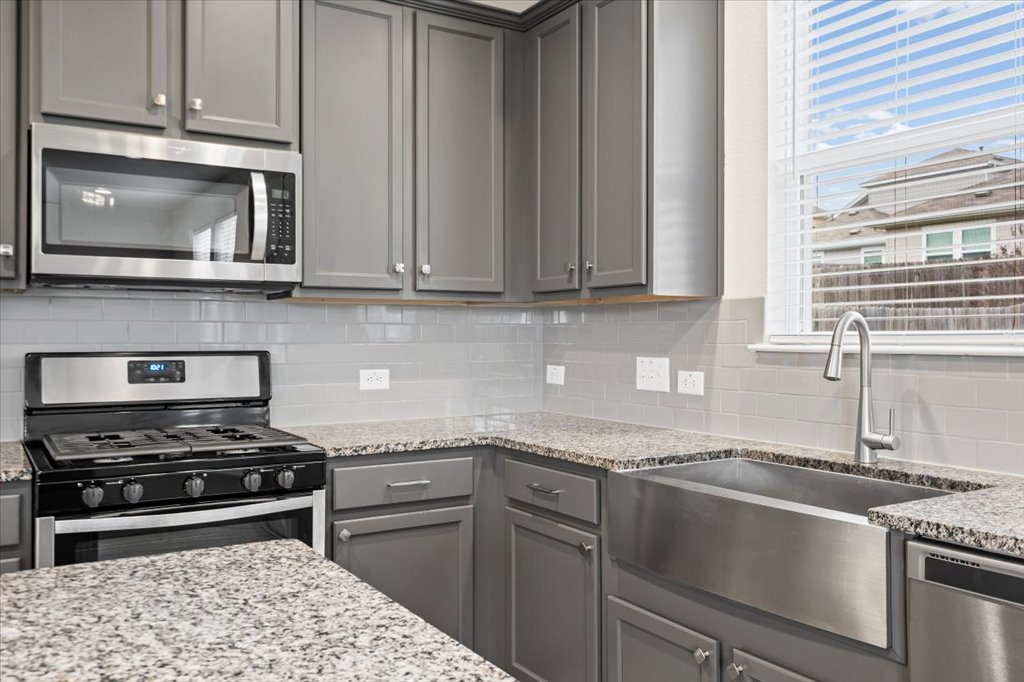 6313 Mary Lewis Drive Austin, TX 78747 - Photo 5 of 20 a kitchen with granite countertop a stove and a microwave
