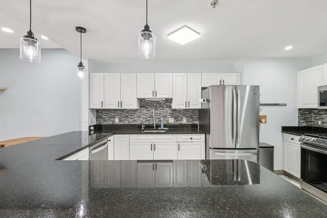 a kitchen with stainless steel appliances granite countertop a stove a sink and a refrigerator