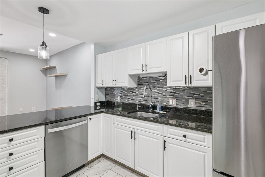 614 Pond Street, Unit 2104 Braintree, MA 02184 - Photo 7 of 29 a kitchen with stainless steel appliances granite countertop white cabinets and white appliances