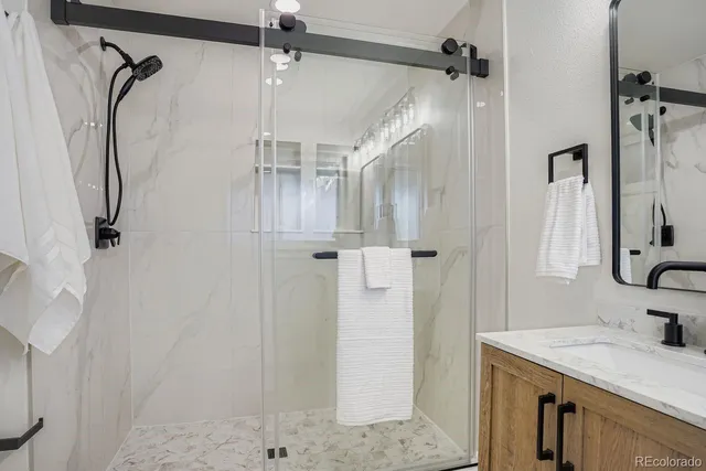 a bathroom with a granite countertop shower sink vanity and mirror