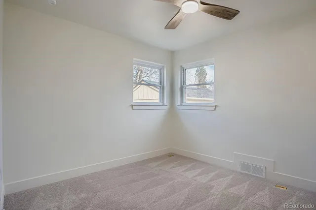 an empty room with a window and a fan