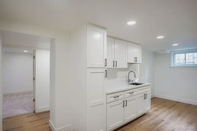 a kitchen with white cabinets and sink