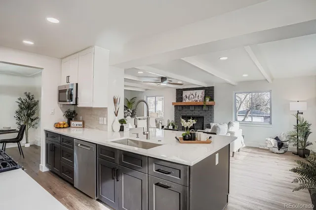 a kitchen with stainless steel appliances a sink stove and wooden floor