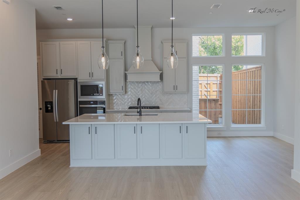 4328 Corn Husk Drive Frisco, TX 75033 - Photo 7 of 22 a large kitchen with stainless steel appliances granite countertop a stove a sink a refrigerator white cabinets and wooden floor