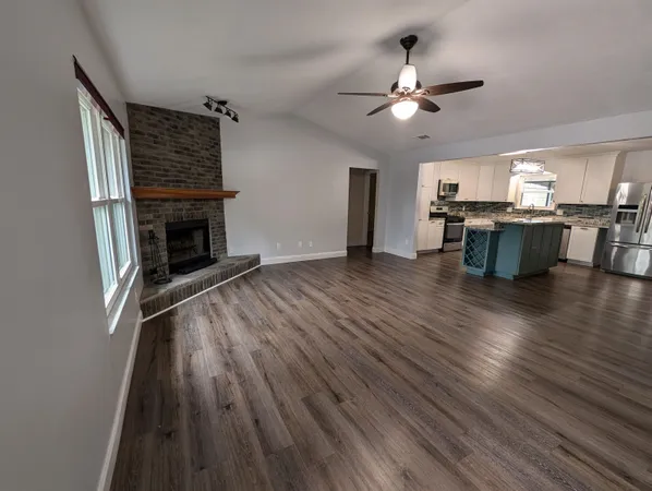 a kitchen with granite countertop wooden floors white cabinets and stainless steel appliances