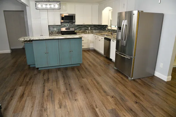 a kitchen with stainless steel appliances a refrigerator and wooden floor