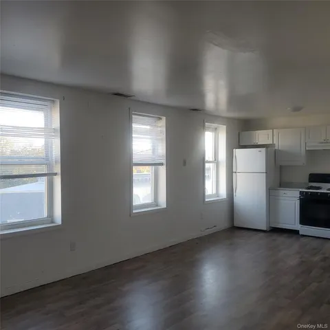 a view of a kitchen with a refrigerator wooden floor and a window