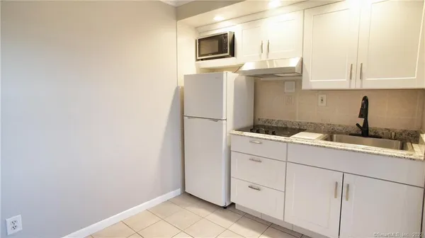 a kitchen with granite countertop white cabinets and stainless steel appliances