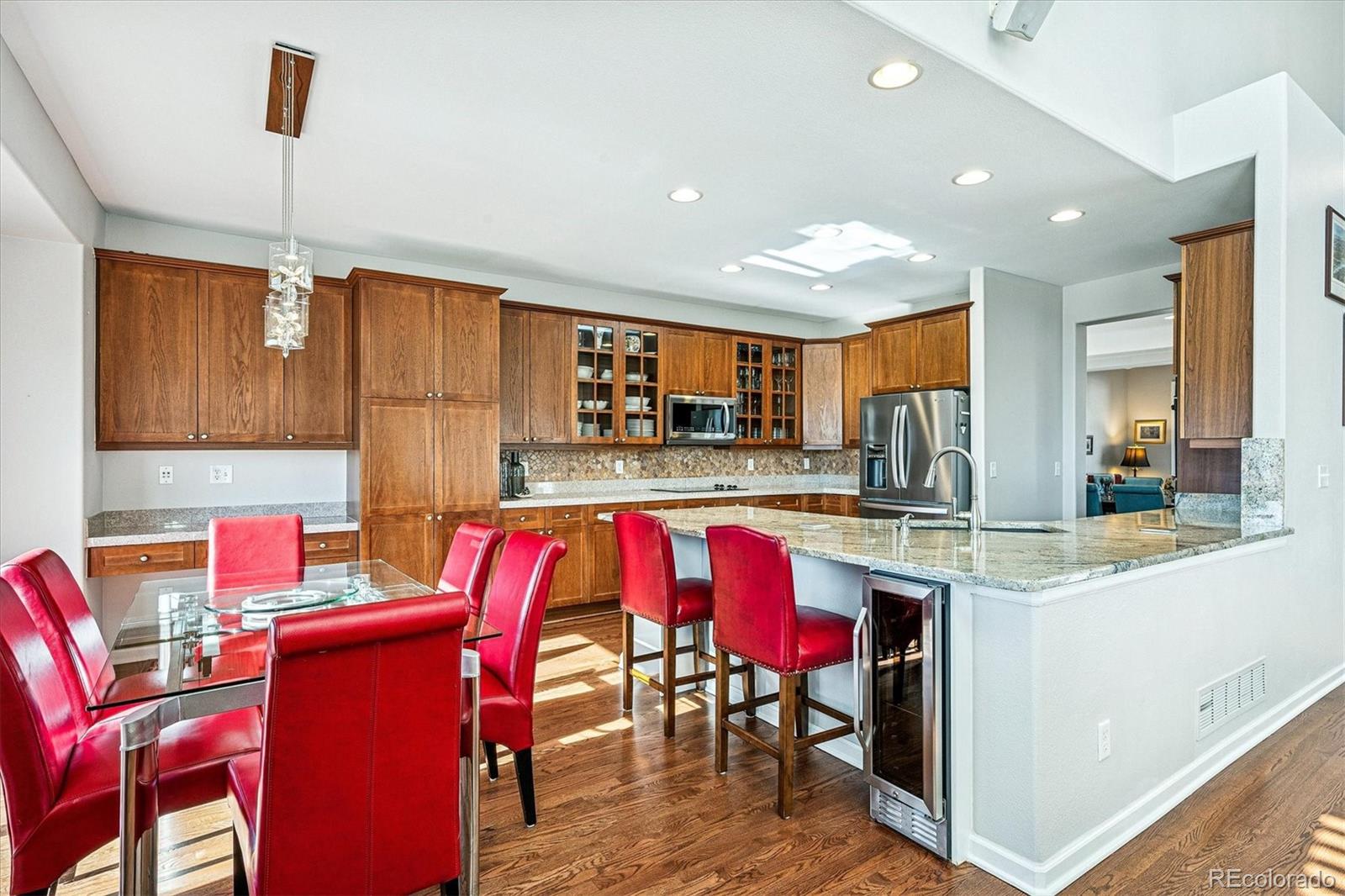 2844 Greensborough Drive Highlands Ranch, CO 80129 - Photo 11 of 42 a kitchen with stainless steel appliances kitchen island granite countertop a dining table chairs refrigerator sink and cabinets