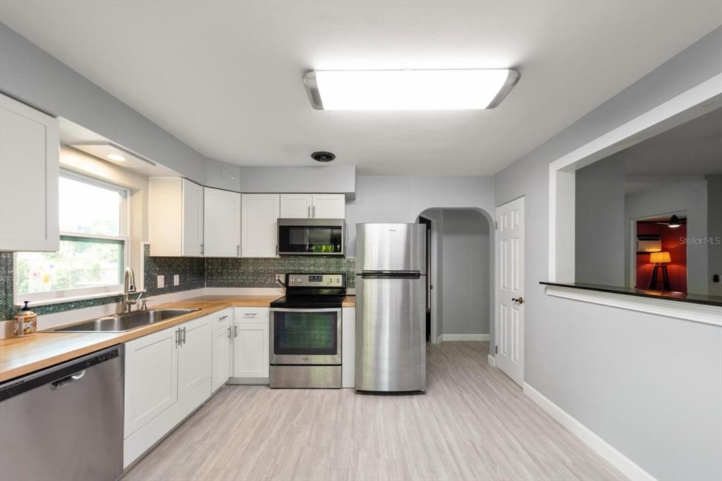 611 11th Street Northwest Largo, FL 33770 - Photo 11 of 37 a kitchen with a refrigerator a sink dishwasher a stove and white countertops with wooden floor