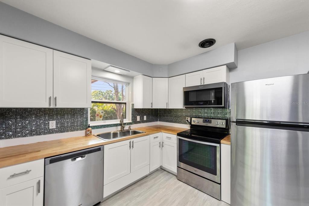 611 11th Street Northwest Largo, FL 33770 - Photo 8 of 37 a kitchen with a refrigerator a sink dishwasher and a stove top oven with wooden floor