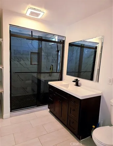 a bathroom with a sink a toilet a mirror and shower