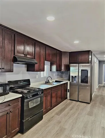 a kitchen with granite countertop wooden cabinets stainless steel appliances and a sink