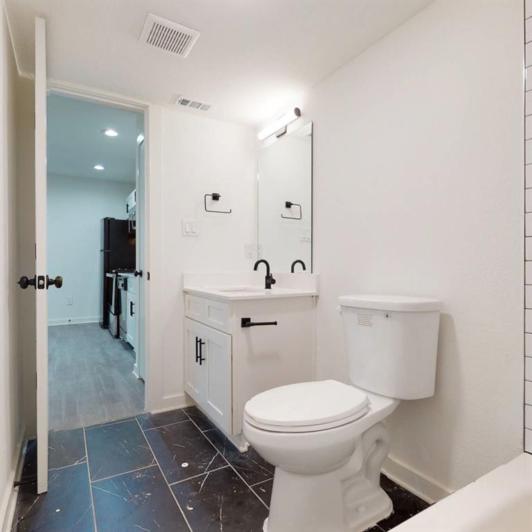 321 East 8th Street, Unit A2 Dallas, TX 75203 - Photo 8 of 14 a bathroom with a toilet a sink and mirror