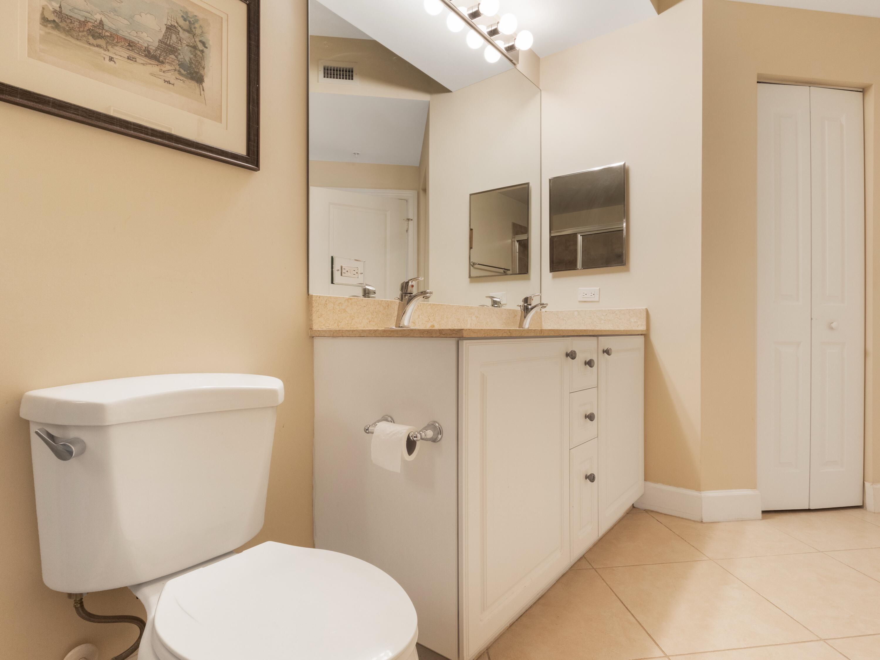 1690 Renaissance Commons Boulevard, Unit 1412 Boynton Beach, FL 33426 - Photo 24 of 49 a bathroom with a toilet a sink and mirror