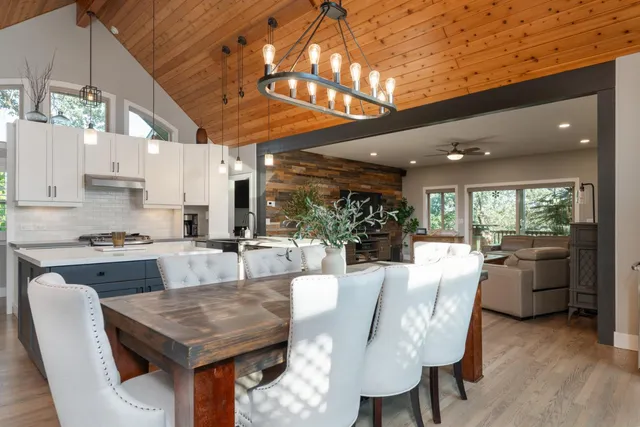 a dining hall with stainless steel appliances granite countertop a stove a kitchen island a table and chairs with wooden floor