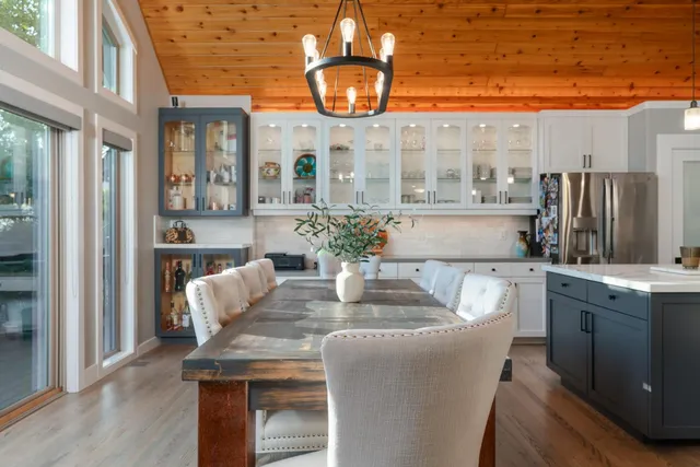 a dining room with furniture a chandelier a large window and stainless steel appliances