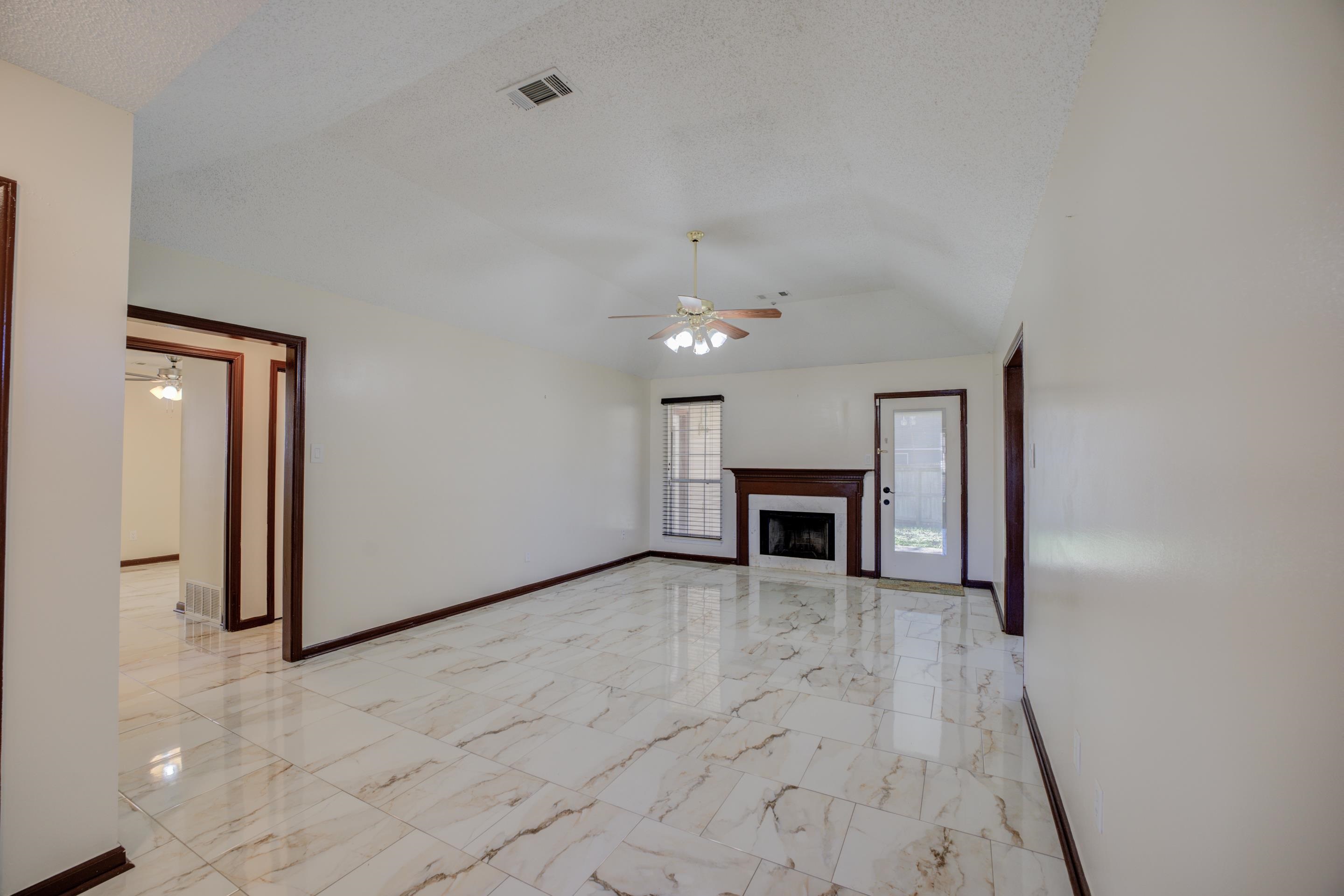 6735 Elmore Ridge Cove Memphis, TN 38134 - Photo 3 of 30 Unfurnished living room with ceiling fan, lofted ceiling, and a textured ceiling