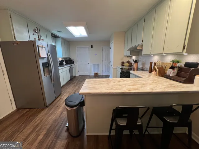 a kitchen with stainless steel appliances kitchen island granite countertop a table chairs and a refrigerator