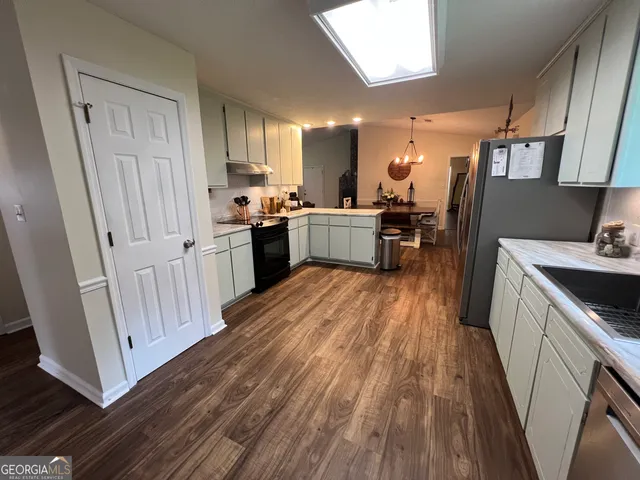 a kitchen with sink a refrigerator and wooden floor