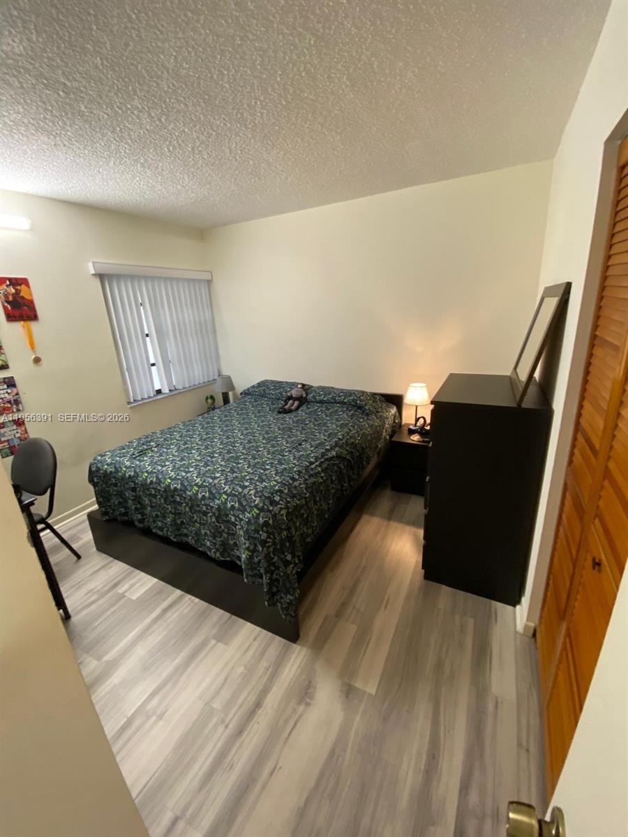 9070 Southwest 125th Avenue, Unit A101 Miami, FL 33186 - Photo 16 of 28 a bedroom with a bed and wooden floor