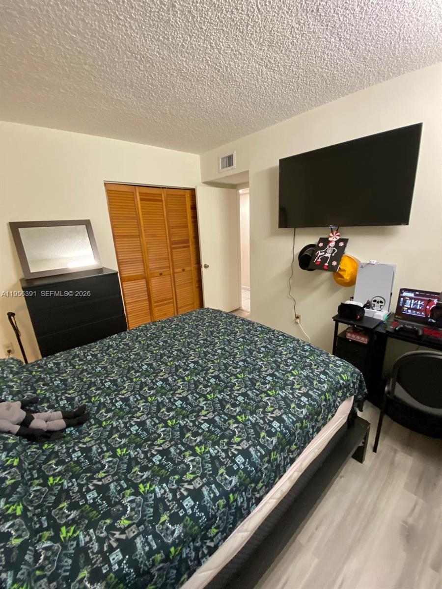 9070 Southwest 125th Avenue, Unit A101 Miami, FL 33186 - Photo 17 of 28 a bedroom with bed and flat screen tv