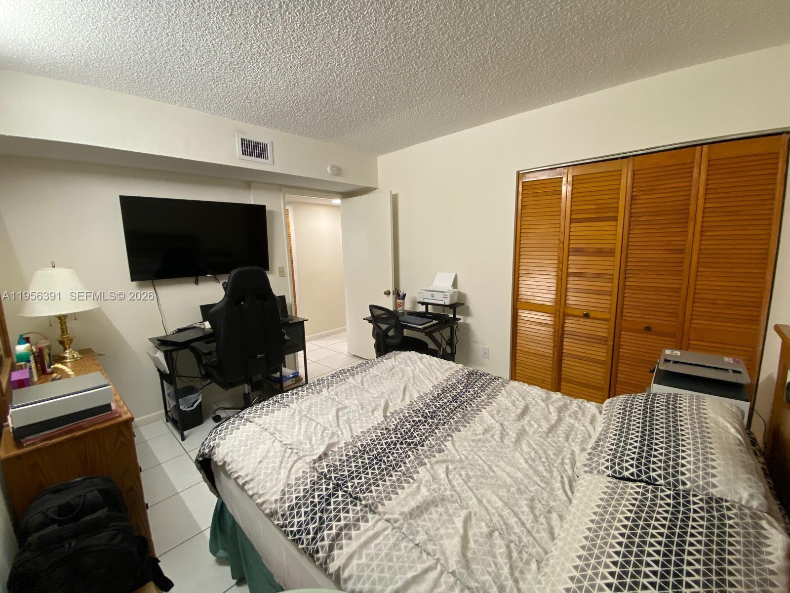 9070 Southwest 125th Avenue, Unit A101 Miami, FL 33186 - Photo 21 of 28 a bedroom with a bed and a flat screen tv
