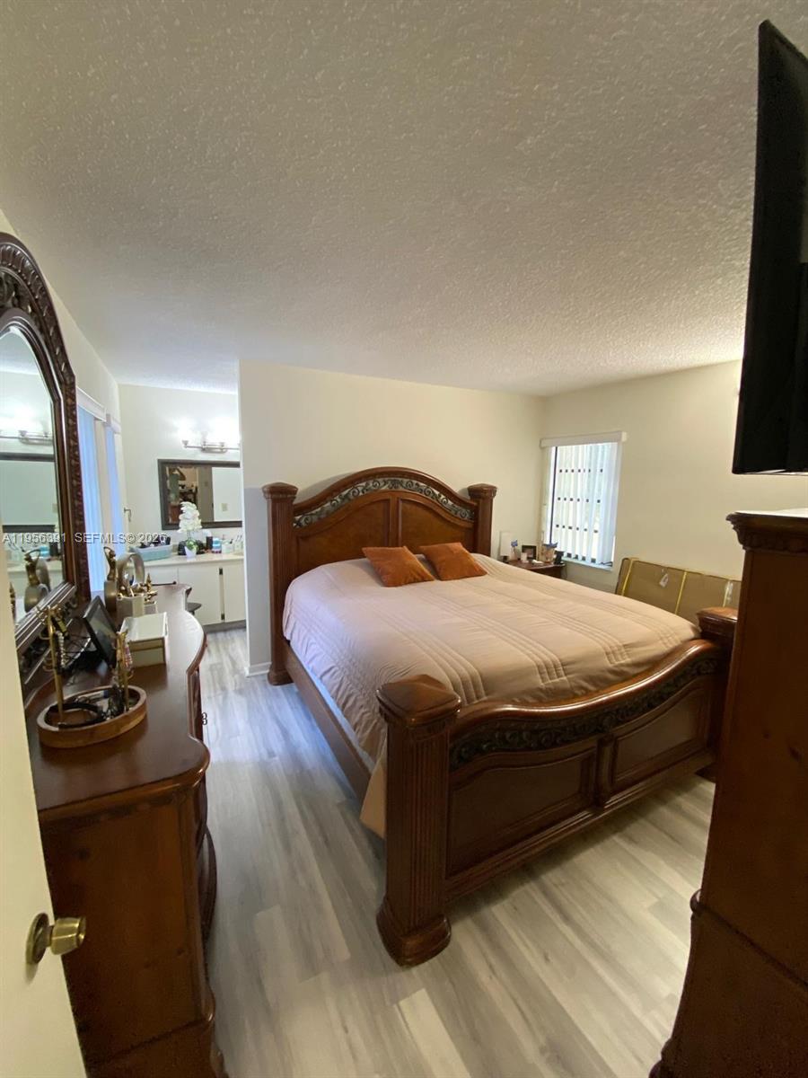 9070 Southwest 125th Avenue, Unit A101 Miami, FL 33186 - Photo 24 of 28 a bedroom with a bed and wooden floor
