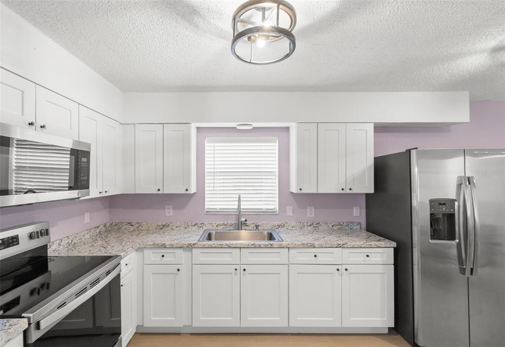 4489 Fishman Avenue Weeki Wachee, FL 34607 - Photo 7 of 29 a kitchen with granite countertop stainless steel appliances a sink cabinets and a window