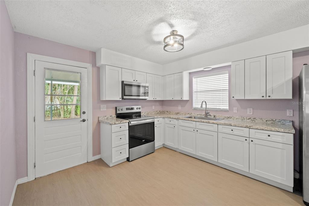 4489 Fishman Avenue Weeki Wachee, FL 34607 - Photo 8 of 29 a kitchen with granite countertop white cabinets and stainless steel appliances