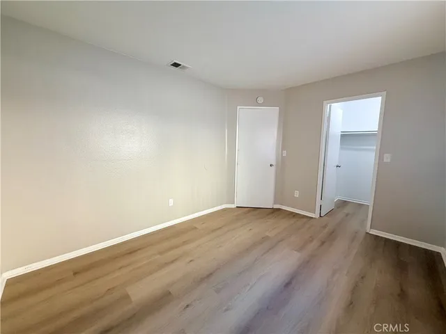 a view of an empty room with wooden floor and closet