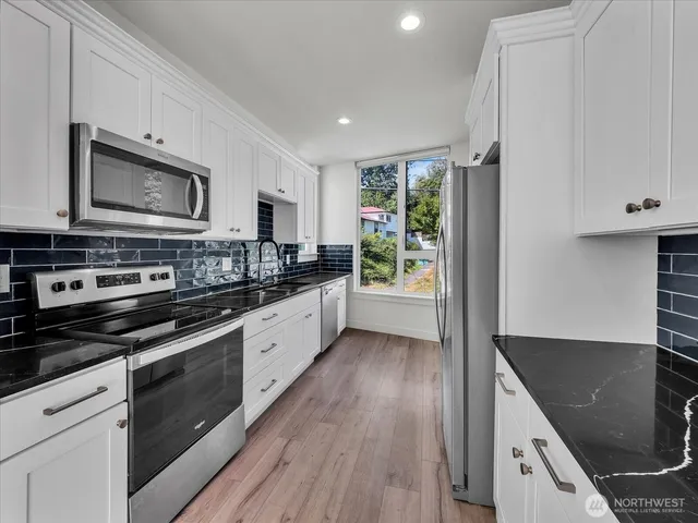 a large kitchen with stainless steel appliances granite countertop a stove a sink and a microwave