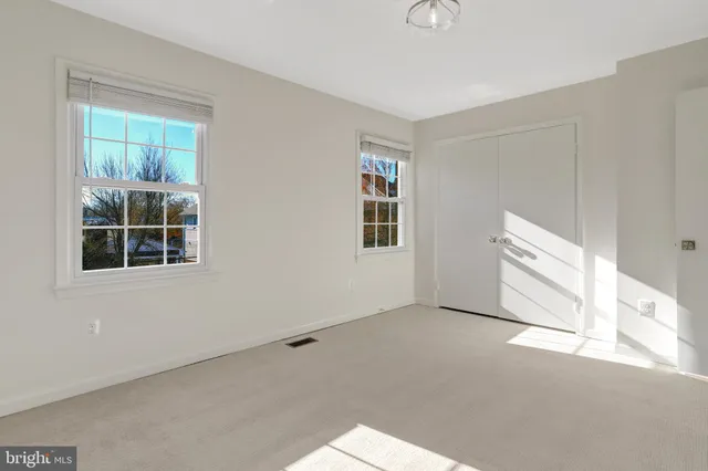 a view of an empty room with window and chandelier fan